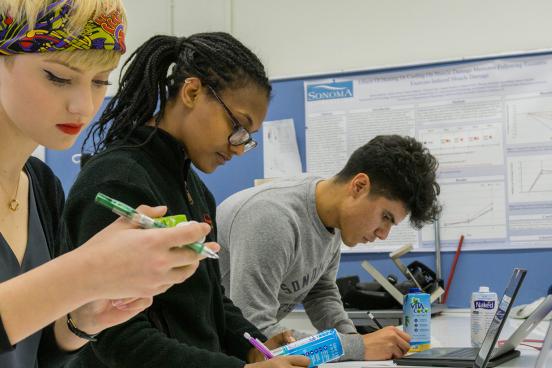 Three students examine items in a classroom lab